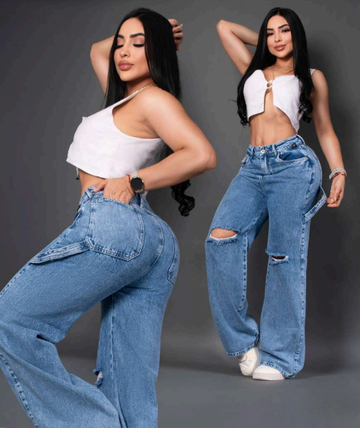 Modelo posando de frente y de espalda con jeans anchos tipo baggy en tono azul medio, con detalles de rotos en las rodillas y tiro alto, resaltando la silueta colombiana.