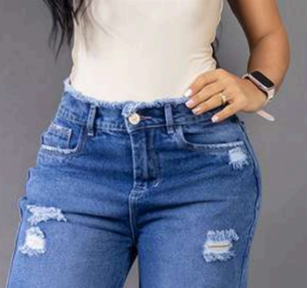 Modelo posando de frente con jeans anchos tipo baggy en tono azul medio, con detalles de rotos y tiro alto, resaltando la silueta colombiana.