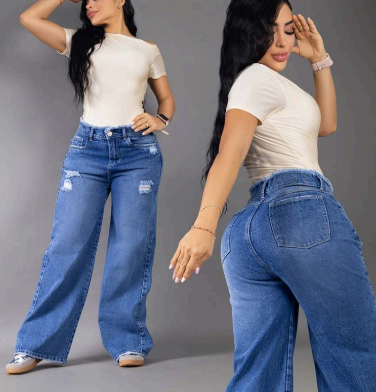 Modelo posando de frente con jeans anchos tipo baggy en tono azul medio, con detalles de rotos y tiro alto, resaltando la silueta colombiana.