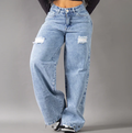 Modelo posando de frente con jeans anchos tipo baggy en tono azul medio, con detalles de rotos en las piernas y tiro alto, resaltando la silueta colombiana.