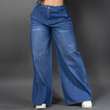 Vistas frontal de una modelo luciendo jeans baggy con un patrón de brillos horizontales en ambas piernas y un parche decorativo brillante. Ancho.