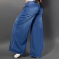 Vistas de lado de una modelo luciendo jeans baggy con un patrón de brillos horizontales en ambas piernas y un parche decorativo brillante. Ancho.