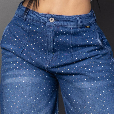 Vistas frontal de una modelo luciendo jeans baggy con un patrón de brillos horizontales en ambas piernas y un parche decorativo brillante. Ancho.
