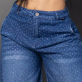 Vistas frontal de una modelo luciendo jeans baggy con un patrón de brillos horizontales en ambas piernas y un parche decorativo brillante. Ancho.