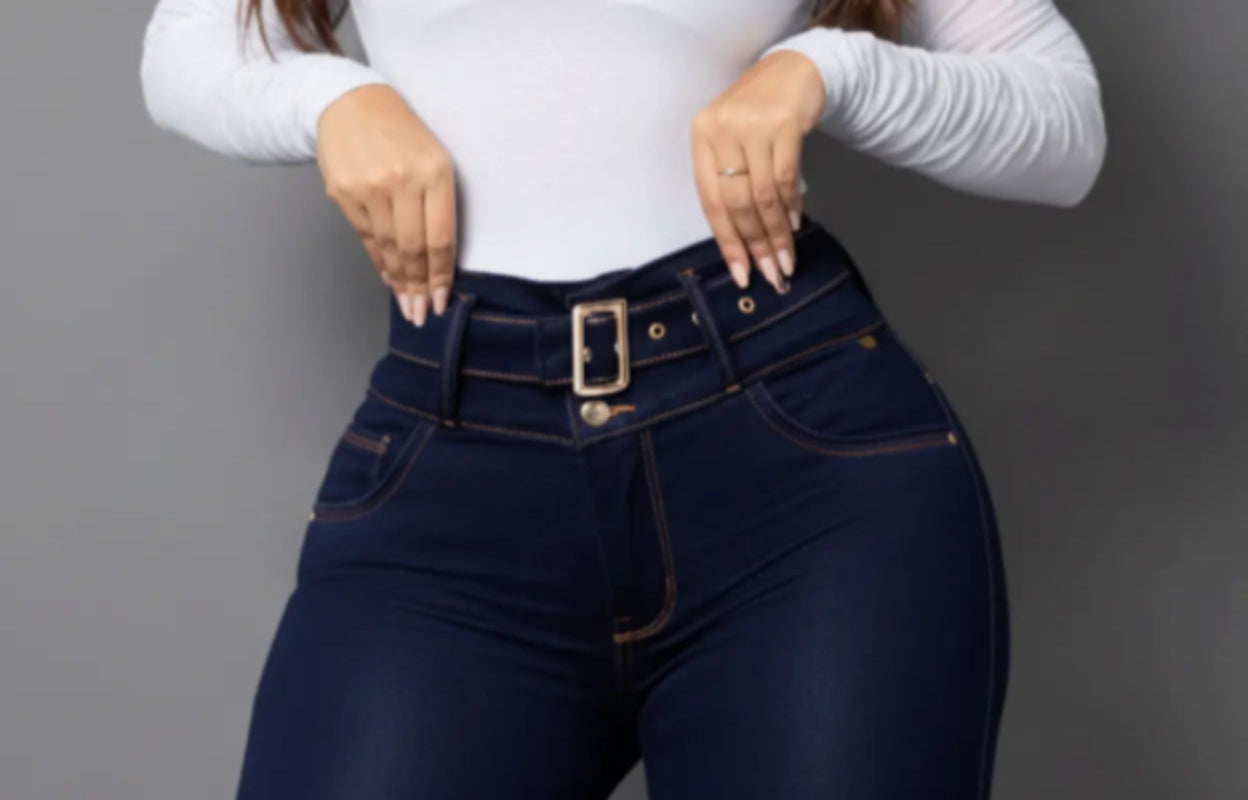 Una modelo de Vengi Fit posa con unos jeans de lavado oscuro de talle alto con cinturón y detalle decorativo en la pretina.