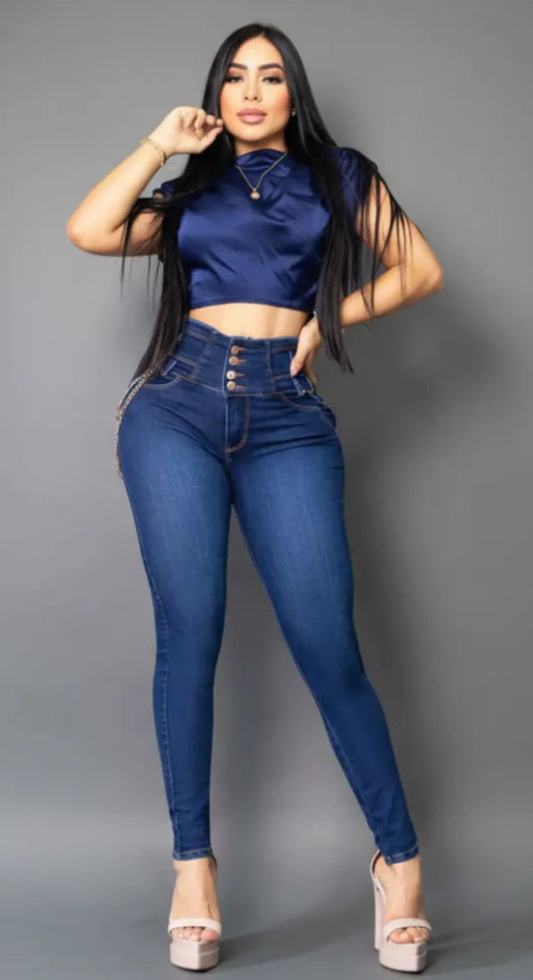 Modelo de lado luciendo jean colombiano azul Vengi Fit con detalle de doble cadena dorada en la cadera y efecto levanta cola.